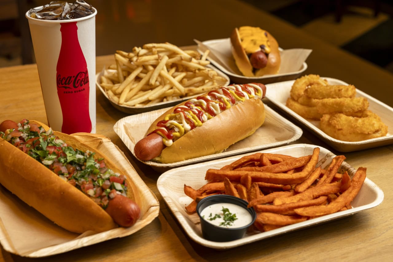 A table set with hot dogs, crispy fries, and a refreshing soda, ready for a casual meal.