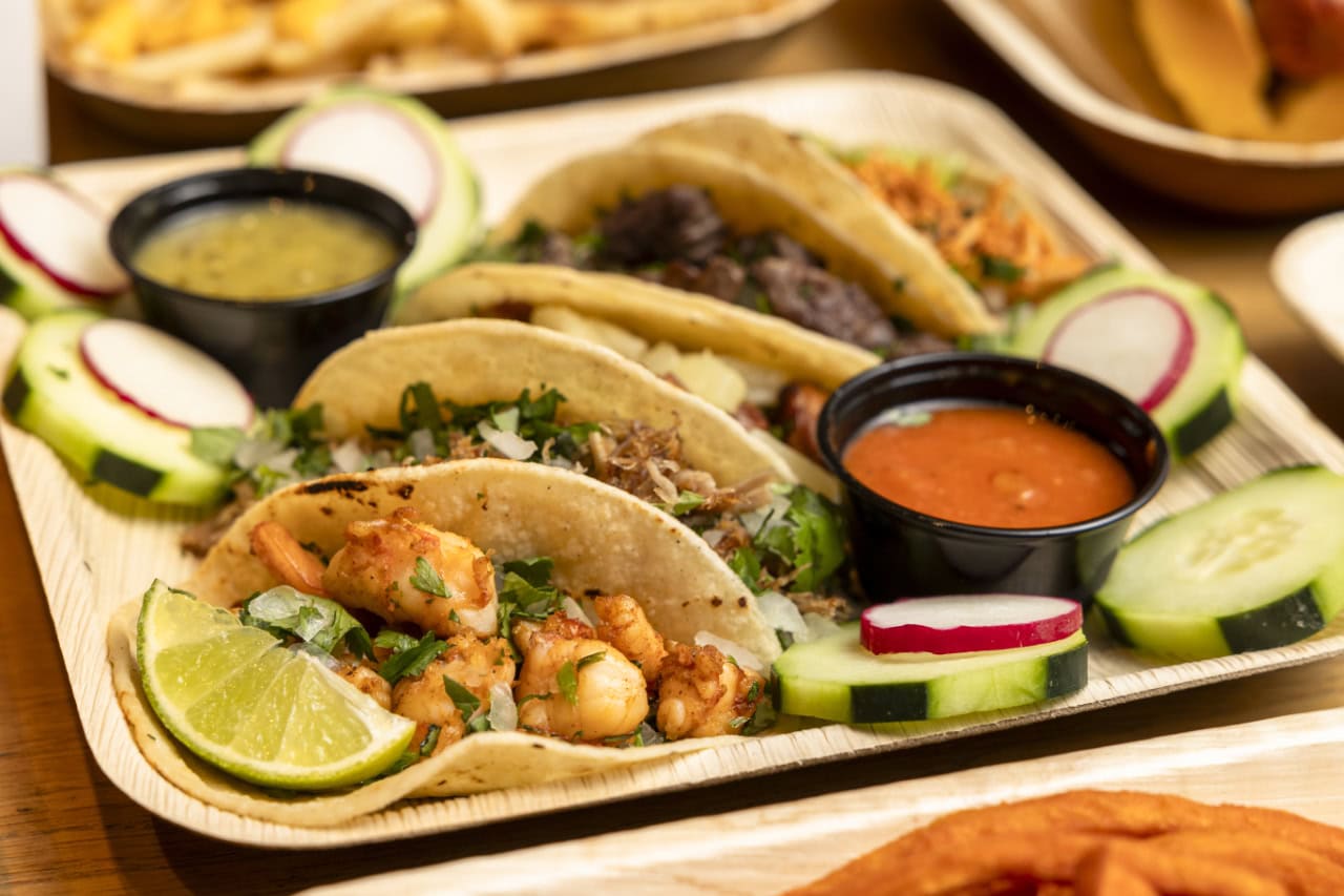 A tray featuring several tacos accompanied by a side of fries and a side of tortilla chips.