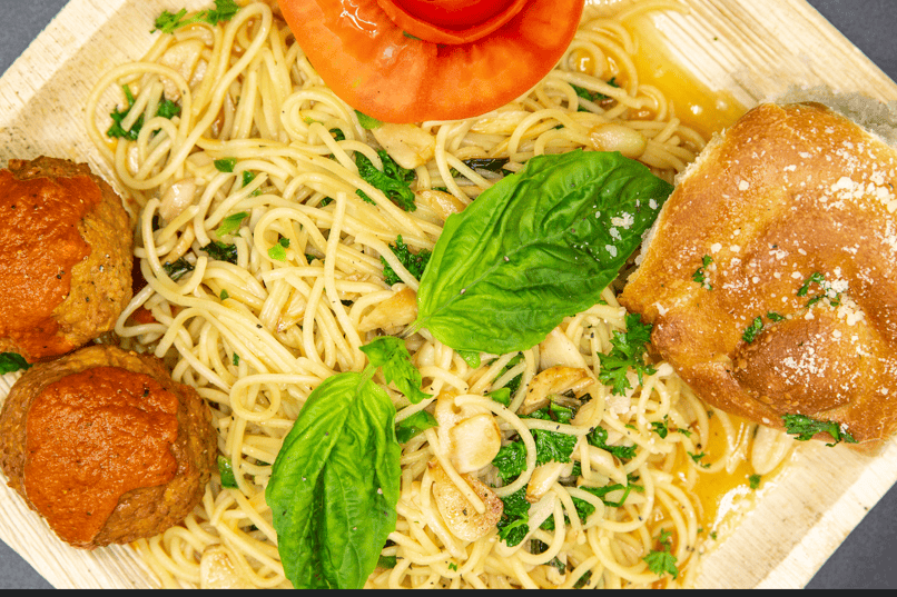 A plate of spaghetti topped with meatballs and garnished with a fresh tomato.