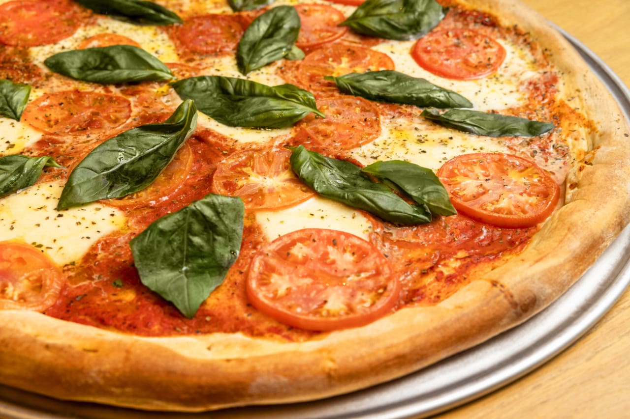 A freshly baked pizza topped with vibrant tomatoes and fragrant basil leaves.