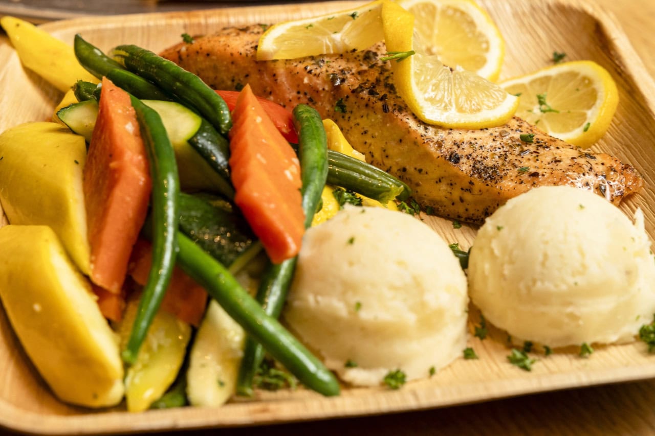 A plate featuring grilled salmon, colorful vegetables, and creamy mashed potatoes arranged appetizingly.